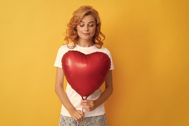 Roodharige dame kijkt naar een romantisch geschenk van liefdadigheid en donatie van een feestballon