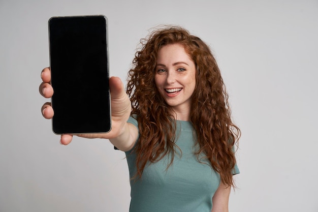Roodharige die het scherm van een mobiele telefoon toont