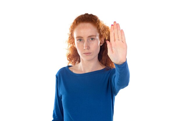 Roodharige jonge vrouw met een casual blauw t-shirt die stopt met zingen met de palm van de hand