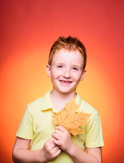 Roodharige jongen Herfstconcept Kopieer ruimte voor reclame Herfstgebladerte Gelukkige jeugd Herfsttrend en herfstmode