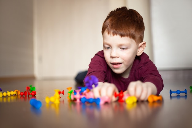 roodharige jongen in een veelkleurige trui spelen