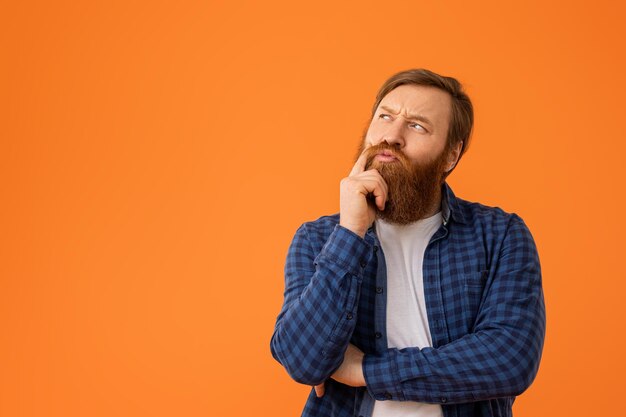 Roodharige man in een geruite shirt die zijn baard aanraakt.