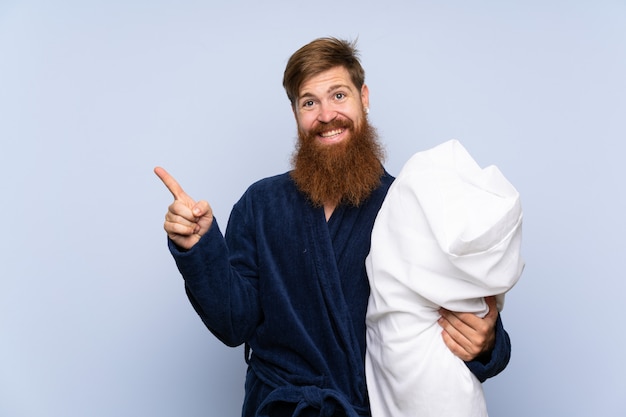 Roodharige man in pyjama wijzend naar de zijkant om een product te presenteren