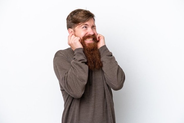 Roodharige man met baard geïsoleerd op een witte achtergrond gefrustreerd en die oren bedekt