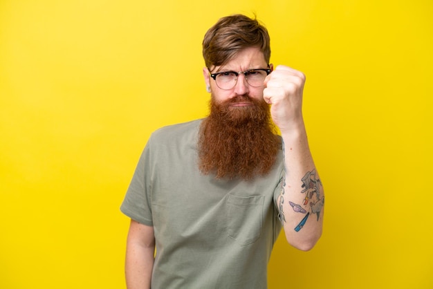 Foto roodharige man met baard geïsoleerd op gele achtergrond met ongelukkige uitdrukking