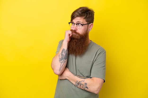 Roodharige man met baard geïsoleerd op gele achtergrond met vermoeide en verveelde uitdrukking