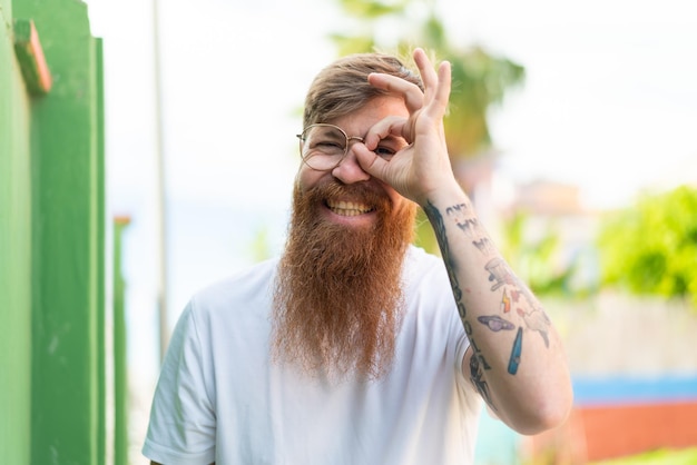 Foto roodharige man met baard met bril met vrolijke uitdrukking