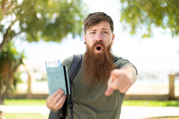 Roodharige man met baard met een paspoort naar buiten verbaasd en naar voren gericht