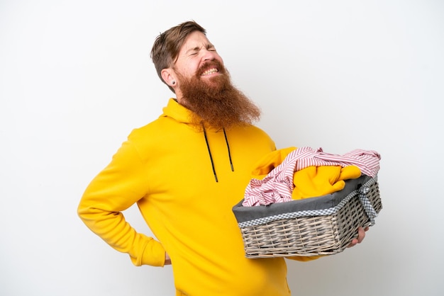 Roodharige man met baard met een wasmand geïsoleerd op een witte achtergrond die lijdt aan rugpijn omdat hij moeite heeft gedaan