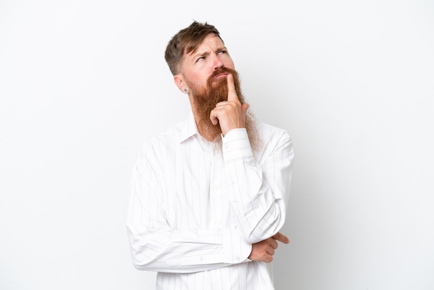 Roodharige man met lange baard geïsoleerd op een witte achtergrond met twijfels tijdens het opzoeken