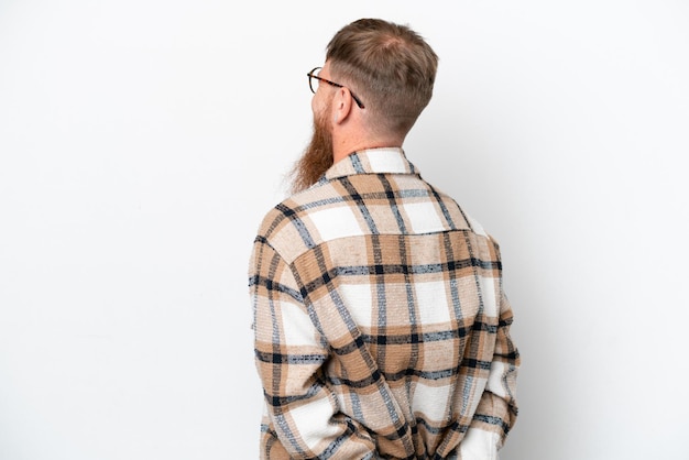 Roodharige man met lange baard geïsoleerd op witte achtergrond in achterste positie en terugkijkend