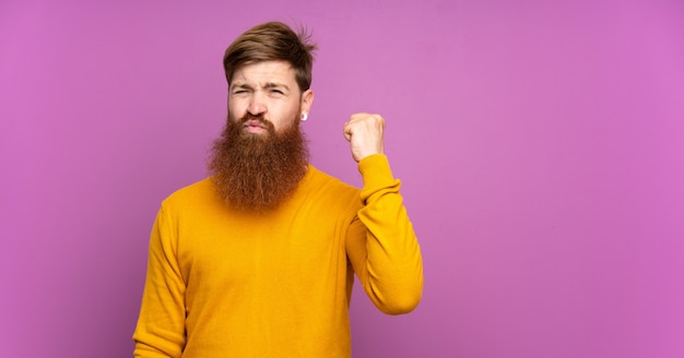 Roodharige man met lange baard over geïsoleerde paars met boos gebaar