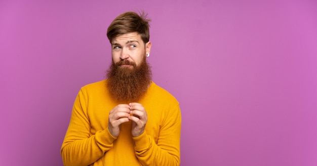 Roodharige man met lange baard over geïsoleerde paarse plannen iets