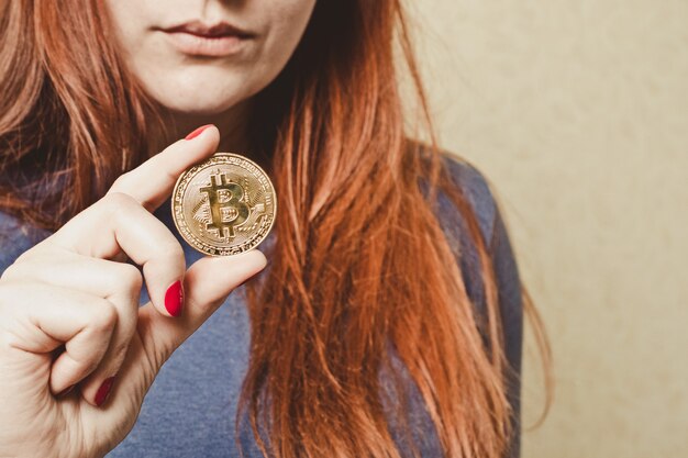 Roodharige meisje houdt bitcoin gouden munt in haar hand