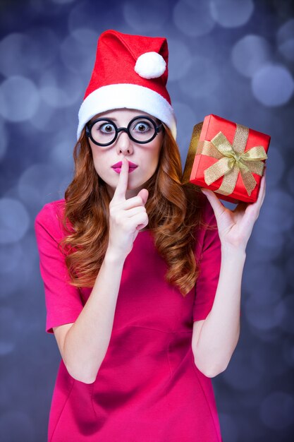 Foto roodharige meisje in kerstmuts met cadeau.