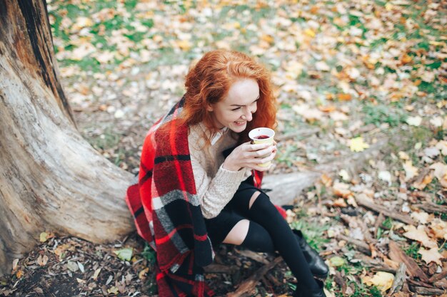 roodharige meisje met koffie in de herfstpark