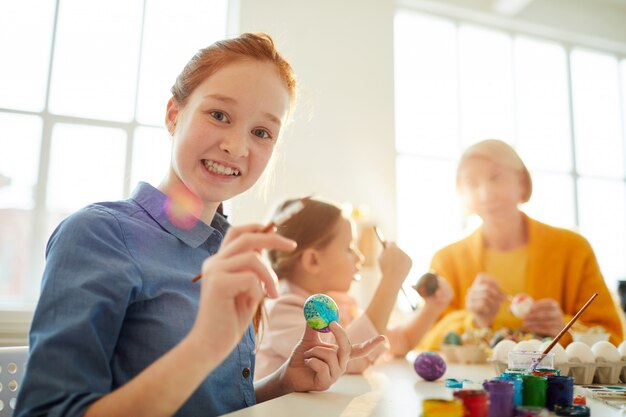 Roodharige meisje schilderij eieren voor Pasen