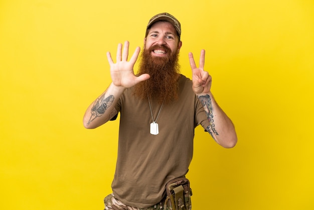 Roodharige Militaire man met dog tag geïsoleerd op gele achtergrond zeven tellen met vingers