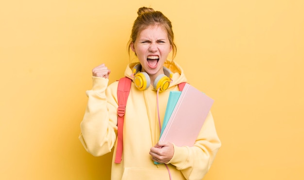 Roodharige mooi meisje agressief schreeuwen met een boze uitdrukking student concept