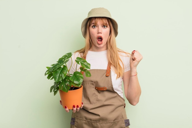 Roodharige mooie vrouw die agressief schreeuwt met een boze uitdrukking. tuinman concept