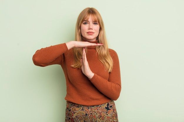 Roodharige mooie vrouw die ernstig streng boos en ontevreden kijkt en een time-out tekent