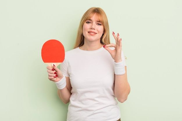 Roodharige mooie vrouw die zich gelukkig voelt en goedkeuring toont met een goed gebaar pingpongconcept