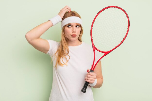 Roodharige mooie vrouw die zich verward en verward voelt, hoofd krabben. tennisconcept