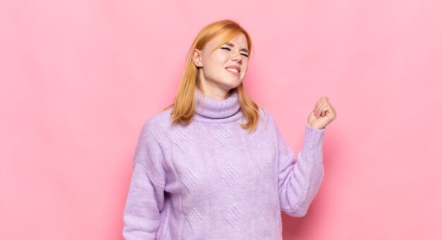 Roodharige mooie vrouw lachend, zich zorgeloos, ontspannen en gelukkig voelen, dansen en naar muziek luisteren, plezier maken op een feestje