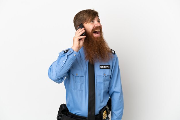 Roodharige politieman geïsoleerd op een witte achtergrond die een gesprek voert met de mobiele telefoon