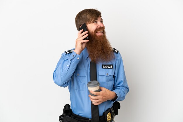 Roodharige politieman geïsoleerd op een witte achtergrond met koffie om mee te nemen en een mobiel