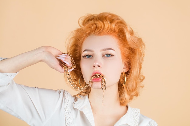 Roodharige vrouw close-up portret met gouden ketting in mond