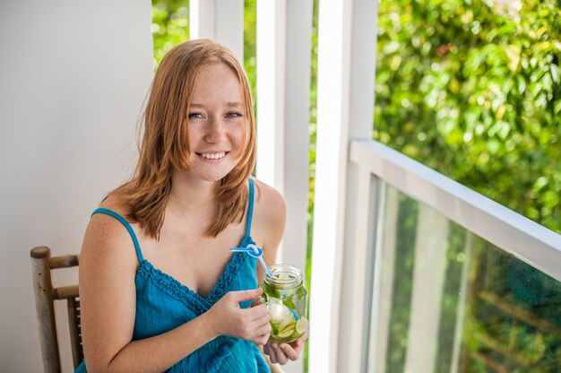 Roodharige vrouw die een mojito op het terras drinkt