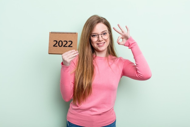 Roodharige vrouw die zich gelukkig voelt, goedkeuring toont met een goed gebaaragenda 2022-concept