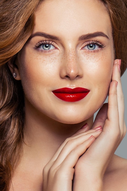 Roodharige vrouw gezicht close-up portret. Rood haar, sproeten, make-up voor rode lippen en rode nagels