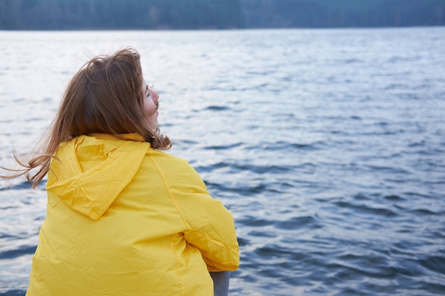 Roodharige vrouw in gele regenjas zitten