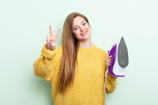 Roodharige vrouw lacht en ziet er gelukkig uit, gebarend overwinning of vrede. ijzeren kleding concept