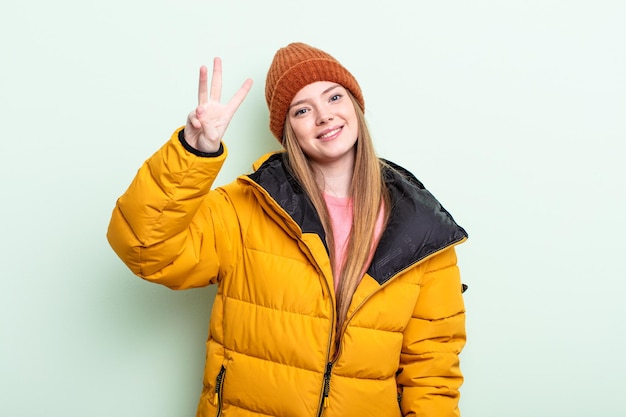 Roodharige vrouw lacht en ziet er vriendelijk uit, met nummer drie. winter concept