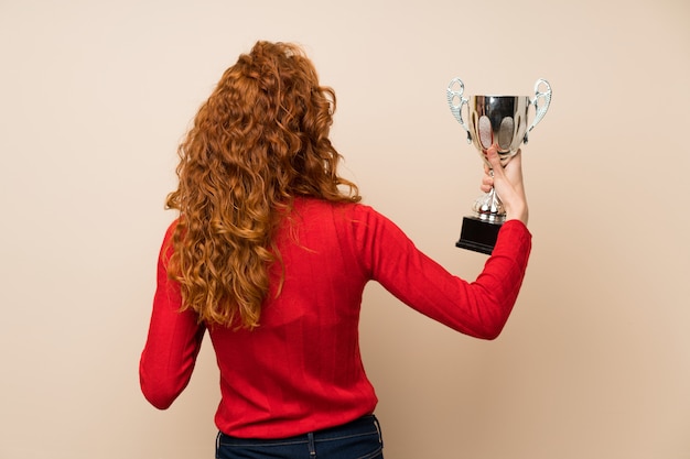 Roodharige vrouw met coltrui trui met een trofee