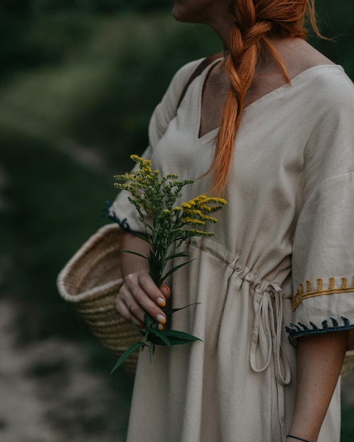 Roodharige vrouw met een gele bloem op het platteland