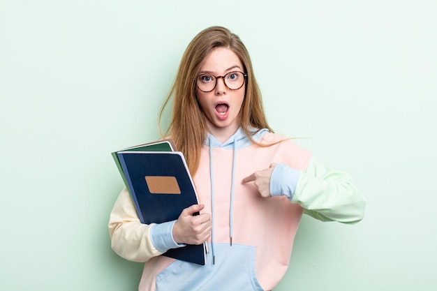 Roodharige vrouw voelt zich gelukkig en wijst naar zichzelf met een opgewonden studentenconcept