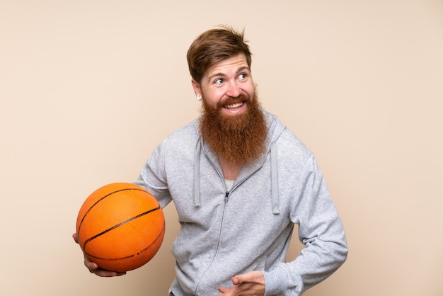 Roodharigemens met lange baard over geïsoleerd met bal van basketbal