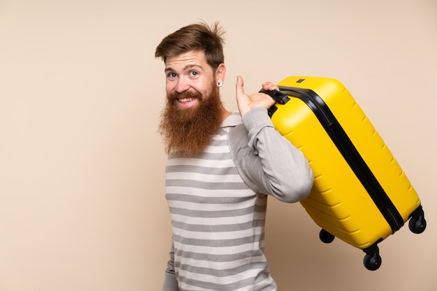 Roodharigemens met lange baard over geïsoleerde achtergrond die een uitstekende aktentas houden