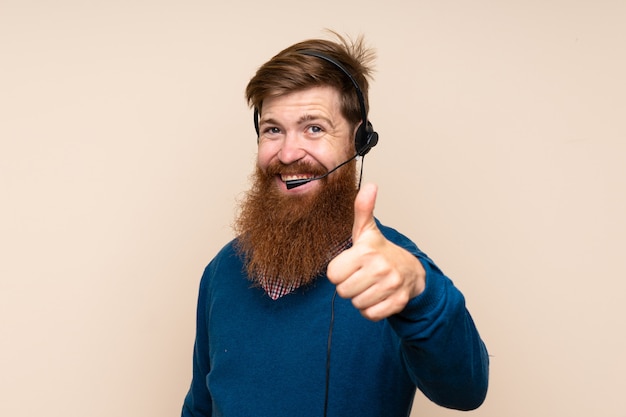 Roodharigemens met lange baard over geïsoleerde achtergrond die met hoofdtelefoon met omhoog duim werken