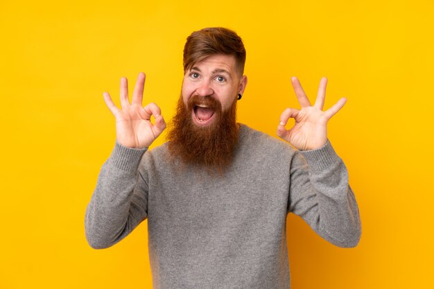 Foto roodharigemens met lange baard over geïsoleerde gele muur die een ok teken met vingers tonen