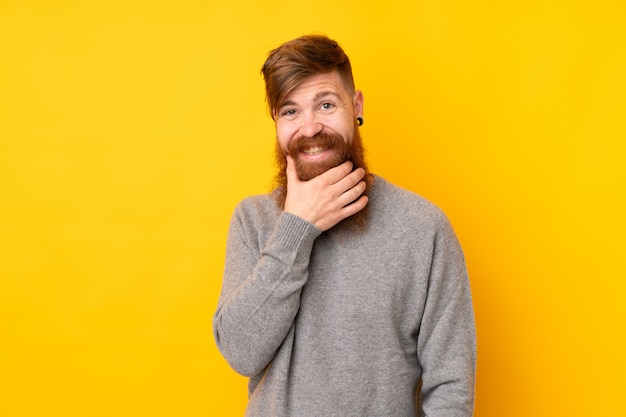 Roodharigemens met lange baard over het geïsoleerde gele muur denken