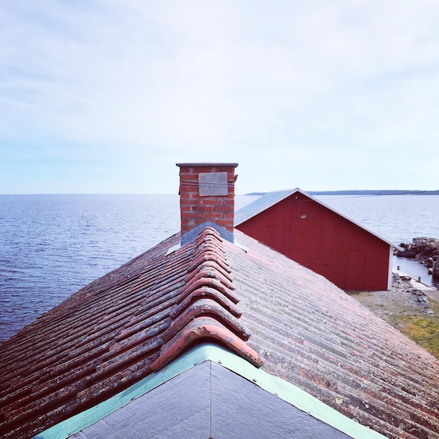 Roof of building by sea against sky