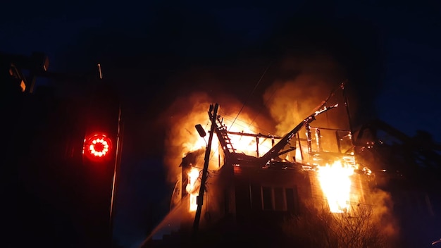 The roof of the house is on fire. the residential building\
burn, village. firefighters put out a fire. fire truck, headlights\
and panel, siren signal.