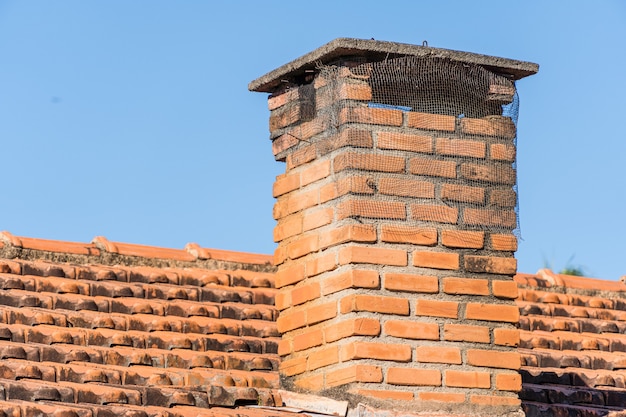 Roof with tiles and red chimney in the interior of Brazil. In the background trees and blue sky.