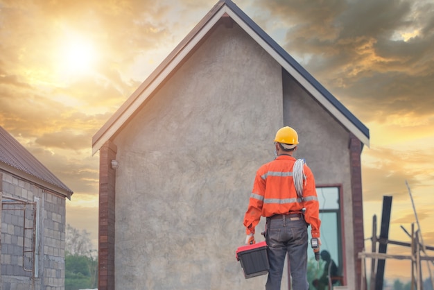 Roofer 건설 노동자는 새 지붕, 지붕 도구, 금속 시트로 새 지붕에 사용되는 전기 드릴을 설치합니다.