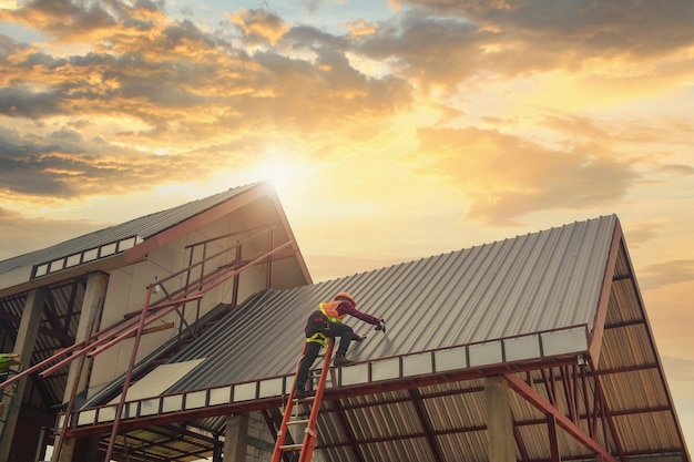 Roofer 건설 노동자는 새 지붕, 지붕 도구, 금속 시트로 새 지붕에 사용되는 전기 드릴을 설치합니다.